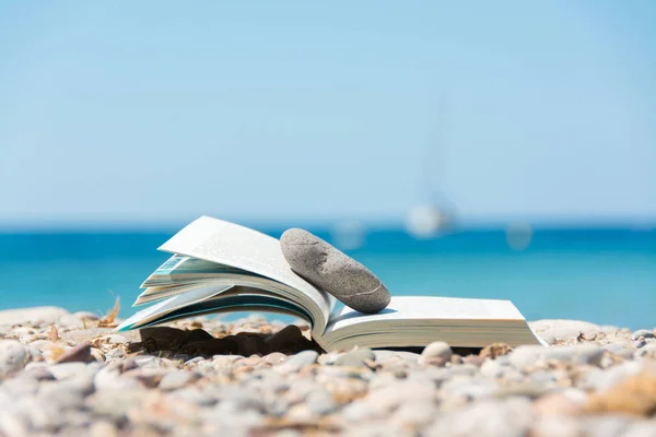 Lectura en vacaciones de verano, concepto. Reserva en la playa de guijarros . —  Fotos de Stock