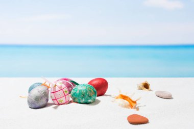 Tropikal plaj arka plan üstünde Paskalya yortusu. Yumurta beyaz kum üzerinde. VAC