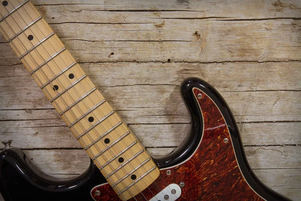 Nahaufnahme einer E-Gitarre, die auf einem Vintage-Holz-Hintergrund liegt, wi — Stockfoto