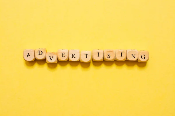 Het Woord Advertising Tekst Gemaakt Met Dobbelstenen Gele Achtergrond — Stockfoto