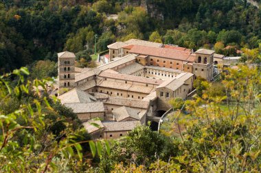 View of Saint Scholastica medieval monastery surrounded, by trees in Subiaco. Founded by Benedict of Nursia clipart