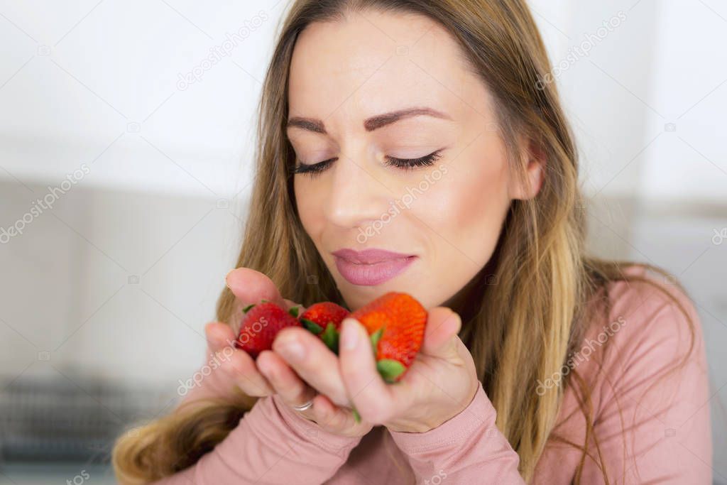 Beautiful girl smelling fresh strawberries