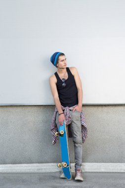 Kaykay üzerinde şehir sokak duvarının yakınında olan genç adam