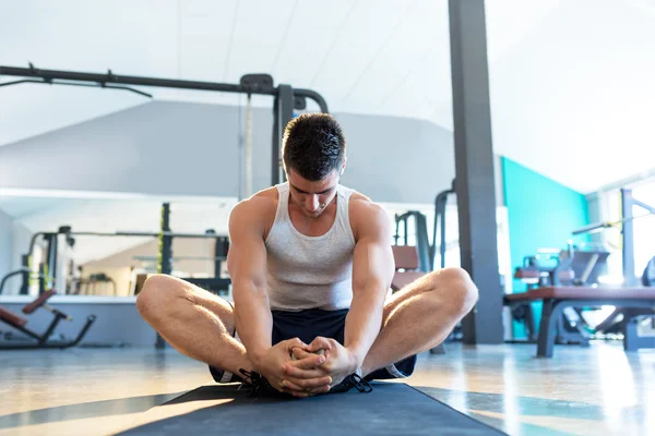 Hombre estirándose en el gimnasio — Foto de Stock