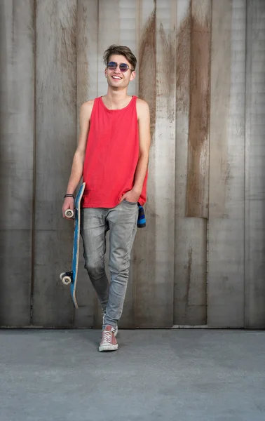 Young man with blue skateboard on city street