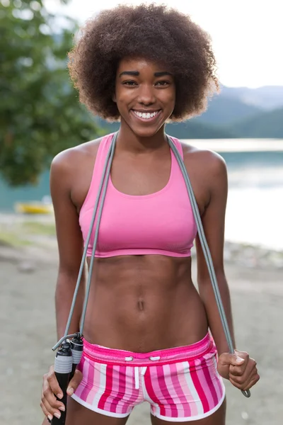 portrait of afro american woman in pink sportswear with jump rope