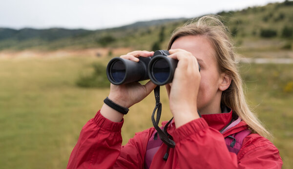 Woman with binoculars hiking in mountains
