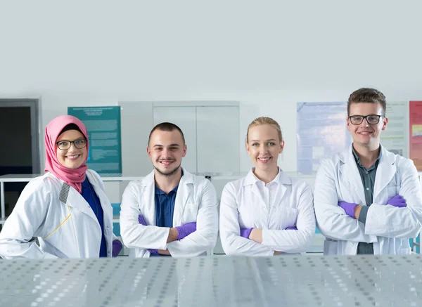 Молодые ученые в белой форме работают в лаборатории — стоковое фото