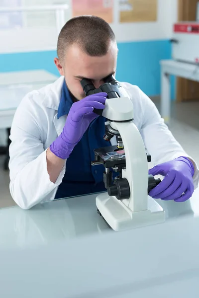 Científico con microscopio en un laboratorio — Foto de Stock