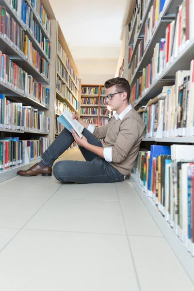Młody człowiek, czytanie w bibliotece — Zdjęcie stockowe