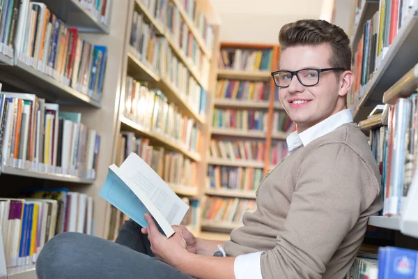 Młody człowiek, czytanie w bibliotece — Zdjęcie stockowe