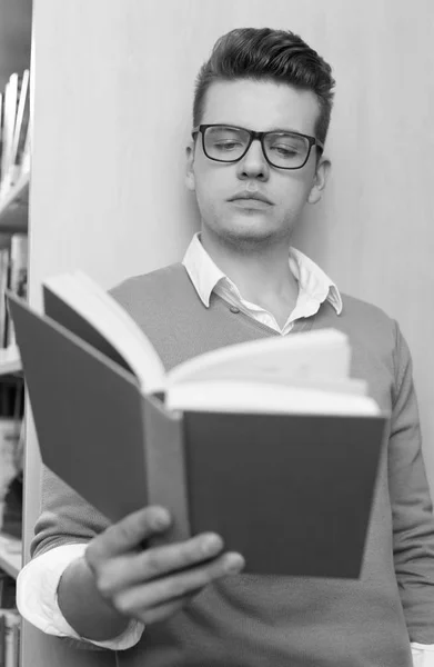 Young man reading in the library — Stock Photo, Image