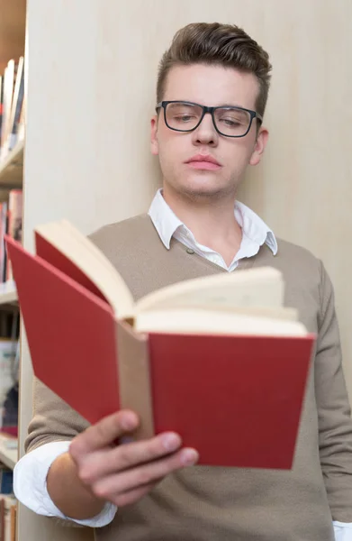 Jovem lendo na biblioteca — Fotografia de Stock