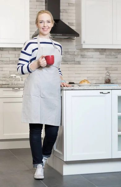在她的厨房里喝咖啡的女人 — 图库照片
