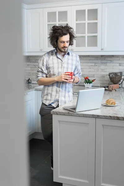 Mężczyzna jedzenie śniadanie podczas przy pomocy laptopa — Zdjęcie stockowe