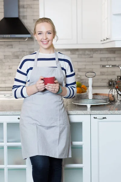 Woman drinking coffee in her kitchen