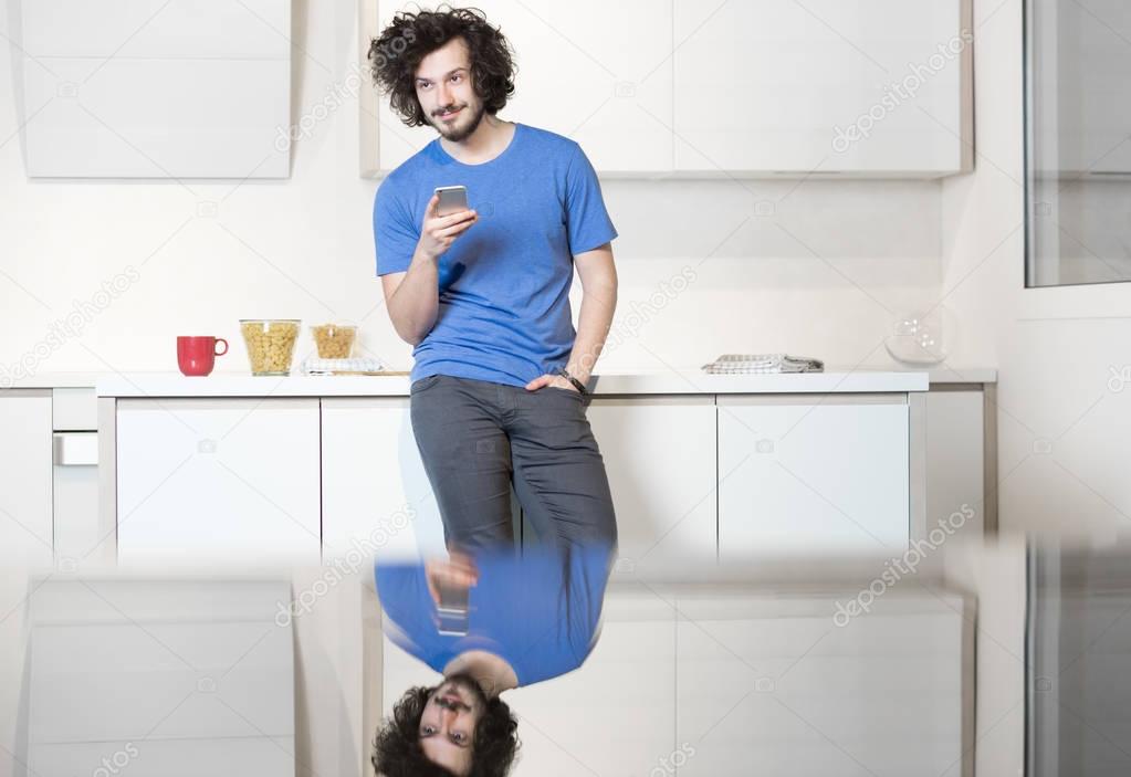 Man in kitchen using cell phone