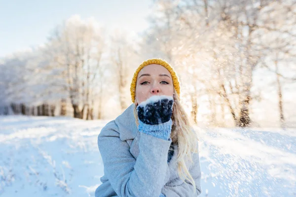 Ragazza nel parco in inverno soffia fiocchi di neve — Foto Stock