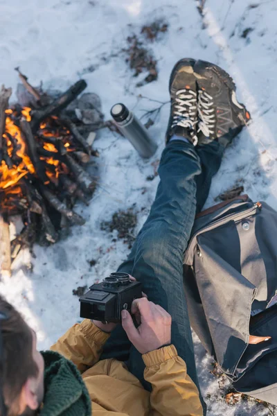 Junge Männliche Wanderer Sitzen Mit Kamera Lagerfeuer Verschneiten Berg lizenzfreie Stockbilder