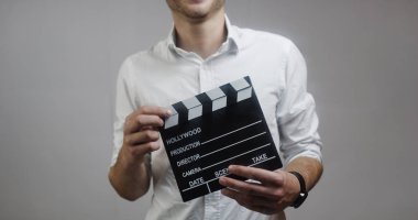 genç adam holding film kurulu gri arka plan üzerinde Beyaz gömlekli Close-Up 