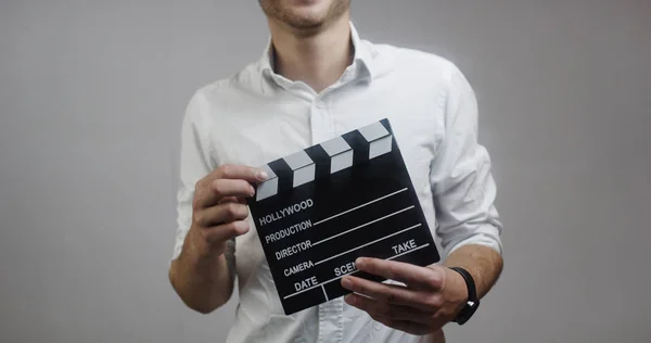 Genç Adam Holding Film Kurulu Gri Arka Plan Üzerinde Beyaz — Stok fotoğraf