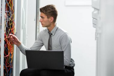 Veri merkezinde çalışan dizüstü bilgisayar ile genç iş adamı