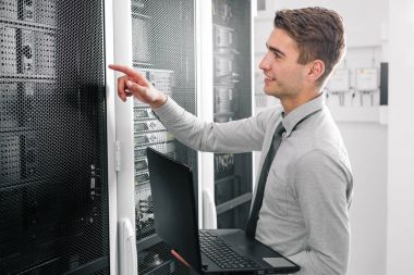 Süper bilgisayarla çalışma sunucu odası laptop ayakta tutan modern genç adam portresi