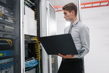 Süper bilgisayarla çalışma sunucu odası laptop ayakta tutan modern genç adam portresi