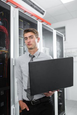 Süper bilgisayarla çalışma sunucu odası laptop ayakta tutan modern genç adam portresi