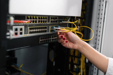 Hand fixing cables in network server room routers clipart