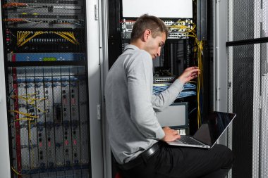 Süper bilgisayarla çalışma sunucu odası laptop ayakta tutan modern genç adam portresi