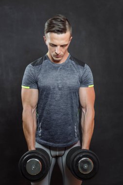 Koyu arka plan üzerinde izole ışık ile Halter atletik genç erkek fitness modeli tutar.