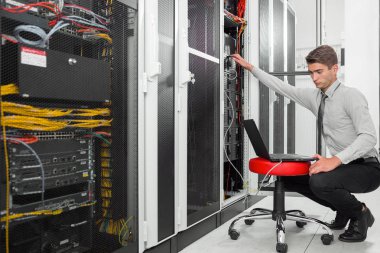 Süper bilgisayarla çalışma sunucu odası laptop ayakta tutan modern genç adam portresi