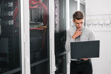 Süper bilgisayarla çalışma sunucu odası laptop ayakta tutan modern genç adam portresi