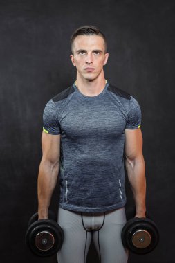 Koyu arka plan üzerinde izole ışık ile Halter atletik genç erkek fitness modeli tutar.