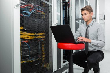 Veri merkezinde çalışan dizüstü bilgisayar ile genç iş adamı