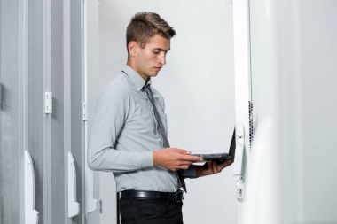 Süper bilgisayarla çalışma sunucu odası laptop ayakta tutan modern genç adam portresi