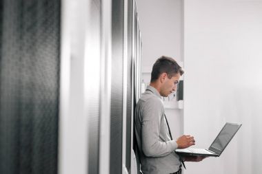 Süper bilgisayarla çalışma sunucu odası laptop ayakta tutan modern genç adam portresi