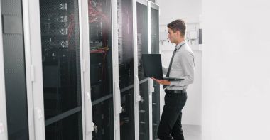 Süper bilgisayarla çalışma sunucu odası laptop ayakta tutan modern genç adam portresi