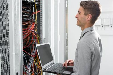 Süper bilgisayarla çalışma sunucu odası laptop ayakta tutan modern genç adam portresi