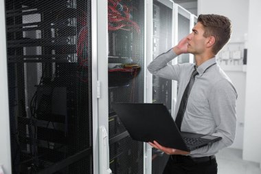 Süper bilgisayarla çalışma sunucu odası laptop ayakta tutan modern genç adam portresi