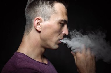 Adam siyah arka plan vaping ve bir bulut bırakmadan üzerinde. 