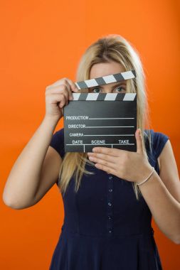 Young woman in action, holding clapperboard. Cinema concept clipart