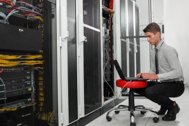 Süper bilgisayarla çalışma sunucu odası laptop ayakta tutan modern genç adam portresi