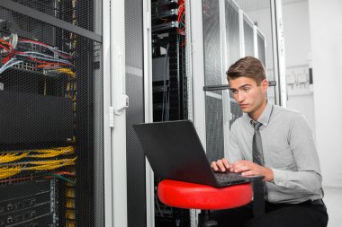 Süper bilgisayarla çalışma sunucu odası laptop ayakta tutan modern genç adam portresi