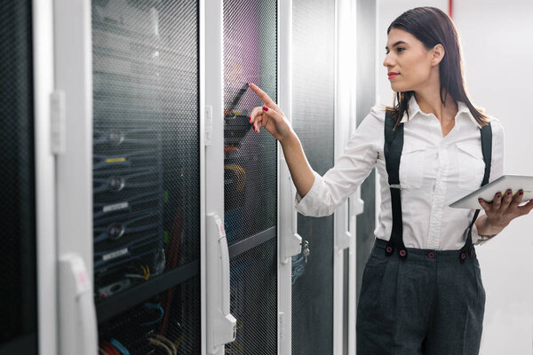 Техник, использующий планшетный компьютер при анализе сервера в большом центре обработки данных
