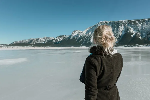 rear view of woman looking at mountain and frozen lake