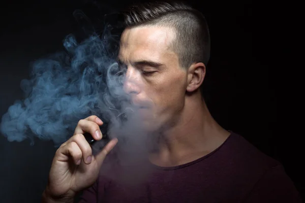 Men on black background vaping and releases a cloud of vapor.