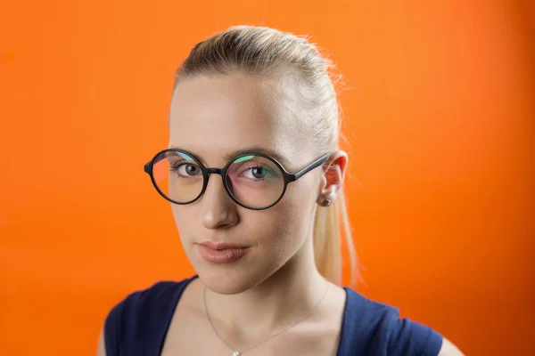 Young Caucasian woman with smiley face wearing glasses on orange background. Vintage style