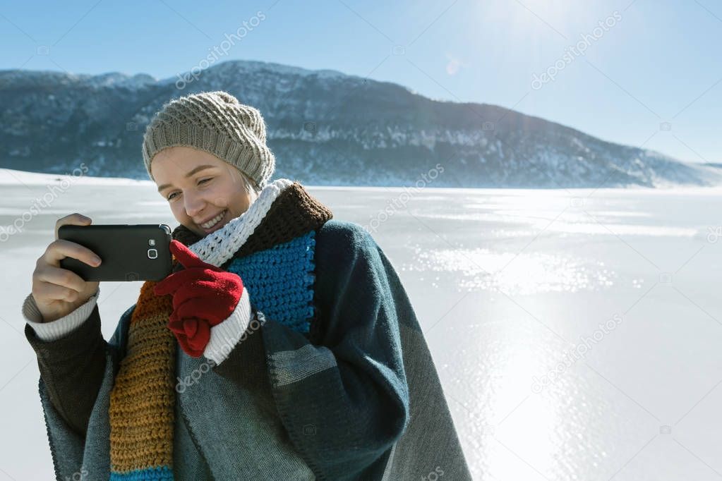 Pretty young female tourist takes selfie in winter